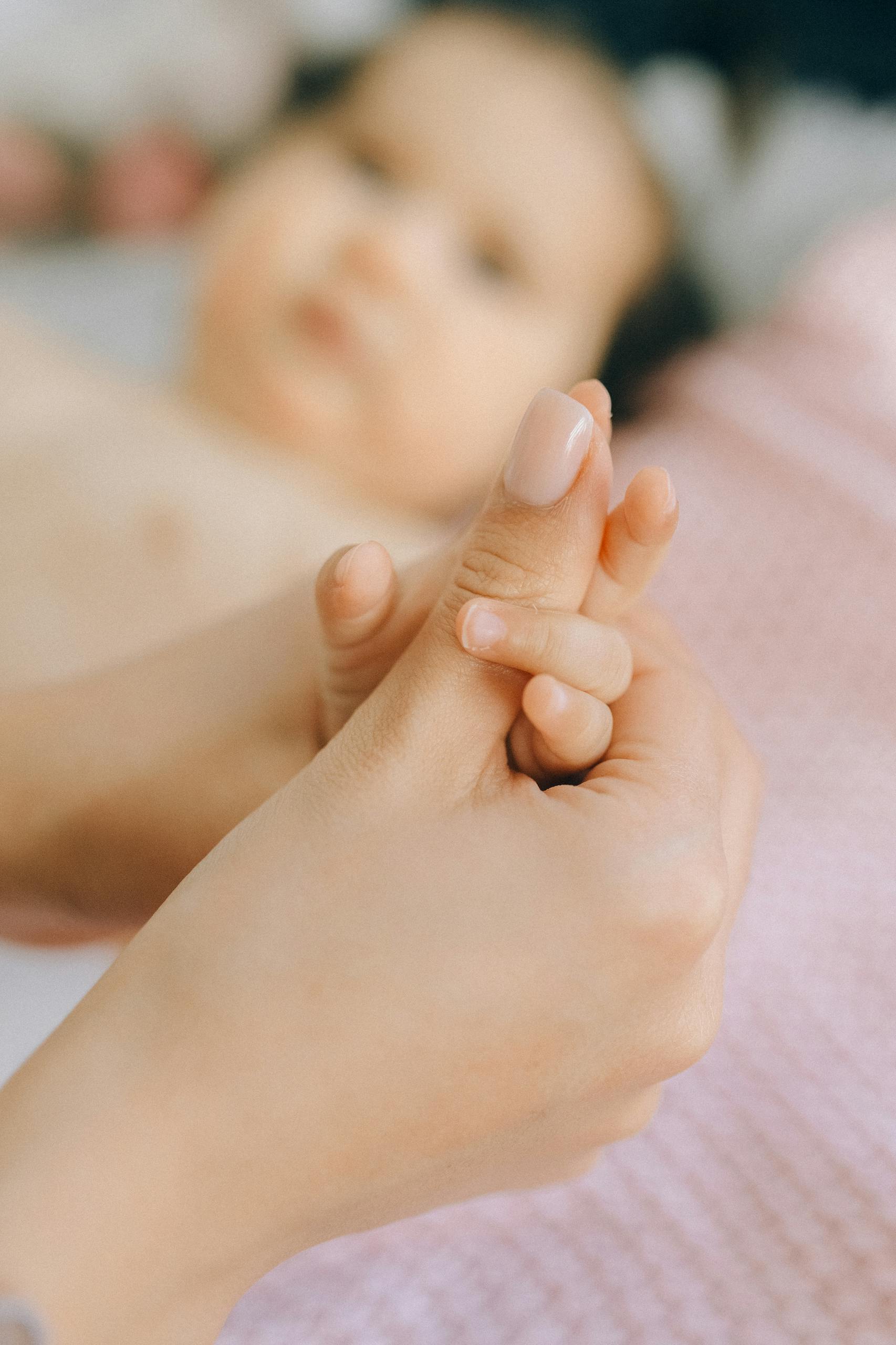 A close-up of a mother gently holding her baby's hand, symbolizing love and care.